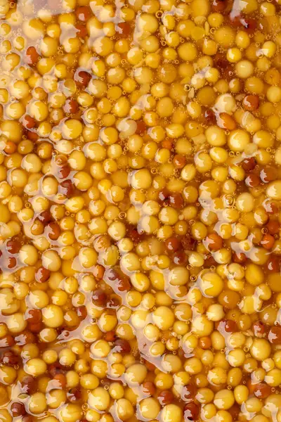 Metal kaşıkta Fransız Dijon hardalı, hardal taneciklerinin arka planda üst görünümü. Gastronomi konsepti, organik gıda. Sos. 