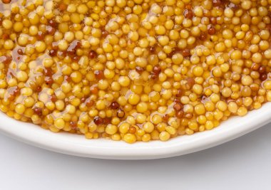 Metal kaşıkta Fransız Dijon hardalı, hardal taneciklerinin arka planda üst görünümü. Gastronomi konsepti, organik gıda. Sos. Çemberde yavaş döndürme.