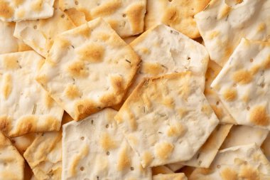 Beyaz arka planda yalıtılmış baharatlı ve otlu tam tahıllı krakerler. Kuru tuzlu kurabiye ve kraker. Bir yığın çıtır buğday, çavdar ve mısır ekmeği susamlı ve ayçiçeği tohumlu tortilla.