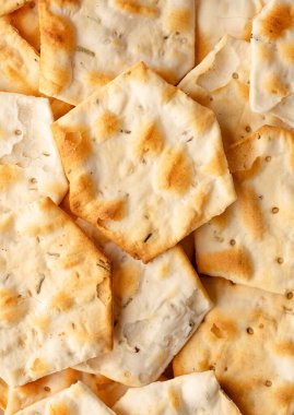 Beyaz arka planda yalıtılmış baharatlı ve otlu tam tahıllı krakerler. Kuru tuzlu kurabiye ve kraker. Bir yığın çıtır buğday, çavdar ve mısır ekmeği susamlı ve ayçiçeği tohumlu tortilla.