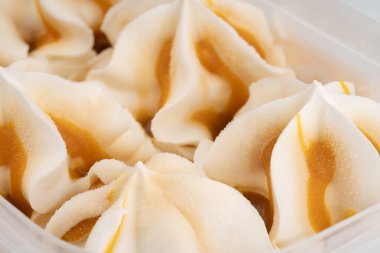 Beyaz arka planda izole edilmiş vanilyalı ve karamelli dondurmalı plastik kap. Küvette dondurulmuş tatlı, kremalı doku..