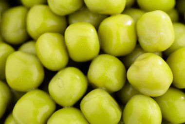 Taze bezelye arkaplanı, arka plan olarak mükemmel soyulmuş bezelye tanelerinin dokusu. Sebze, sebze proteini, sağlıklı ürünler. Bezelye konservesi. bir çember içinde dönüyor