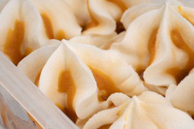 Vanilyalı plastik kap ve karamelli dondurma. Küvette dondurulmuş tatlı, kremalı doku..