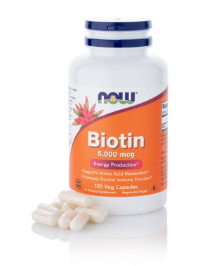 Dnipro, Ukrayna - 09.09.2023: Bir şişe Biotin 5,000 mcg kadın elinde. Şimdi Gıda, bir Biotin Vejetaryen gıda takviyesi.