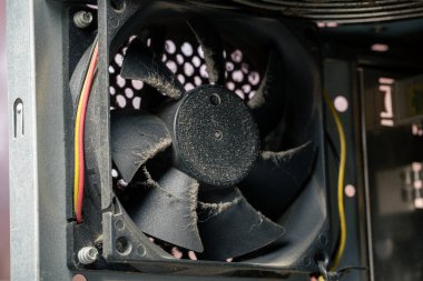 Tozlu bir bilgisayar çantasının yakın plan görüntüsü eski bir bilgisayarın içindeki havalandırma vantilatörünü soğutuyor. Bıçaklarda toz birikintisi olan kirli bir donanım. Bilgisayar bakımı ve aşırı ısınma sorunu.