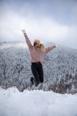 Happy young girl jumping over sky and snow winter background