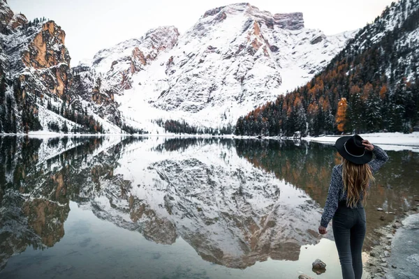 Traveler woman standing on the lake shore and watching the mountains 