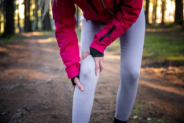 ワークアウトの概念からの傷害 白人女性は森のトレーニングで実行している間 彼女の痛みを伴う膝の上に手を使用します — ストック写真