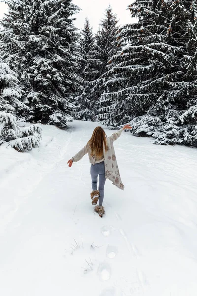 Winter walk, a young beautiful blonde in winter clothes walking in a snowy forest, a beautiful frosty day. happy woman warms a long white scarf.
