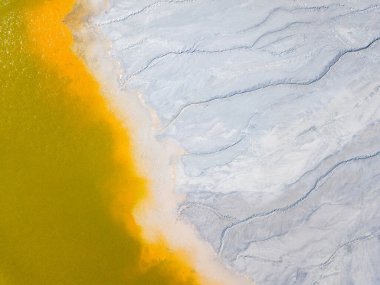 Aerial view of an abandoned Romanian village drowned beneath toxic lake of fluorescent yellow sludge in Geamana,Rosia Montana,Transylvania. Yellow, orange, white abstract background. clipart