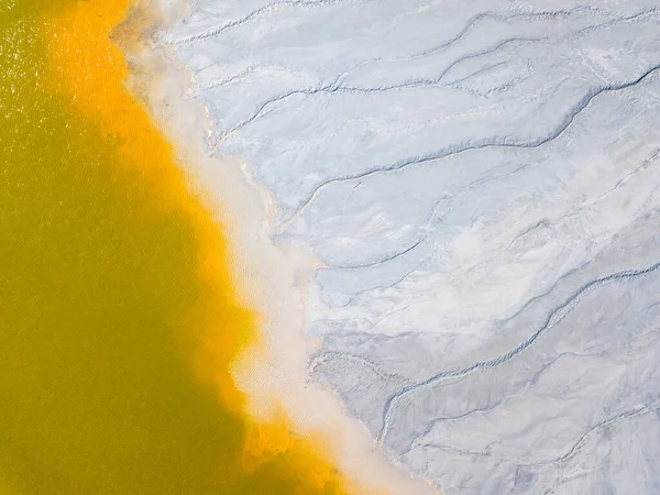 Aerial view of an abandoned Romanian village drowned beneath toxic lake of fluorescent yellow sludge in Geamana,Rosia Montana,Transylvania. Yellow, orange, white abstract background.