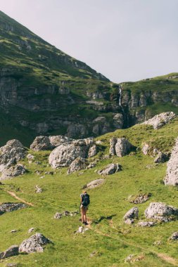 Hiker woman walking in the mountains near the waterfall