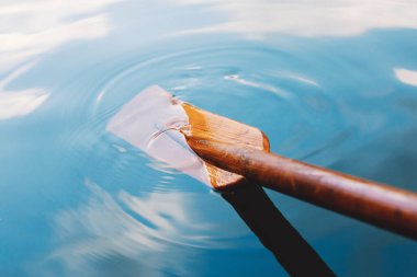 Close up of wooden paddle in the blue clear lake