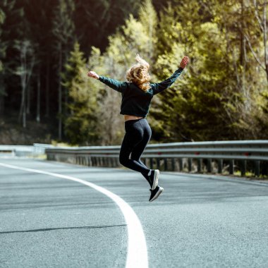 Young girl jumping on the empty road. Healthy lifestyle concept