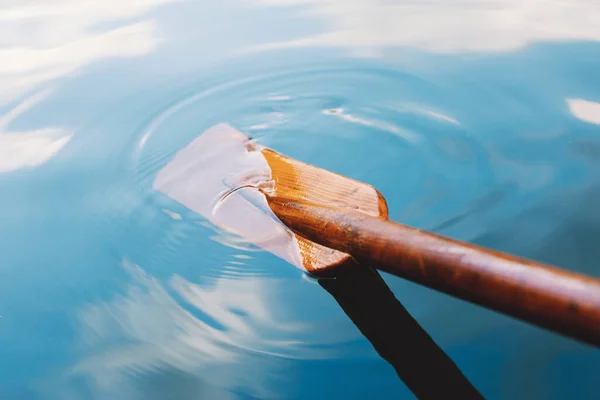 Close up of wooden paddle in the blue clear lake