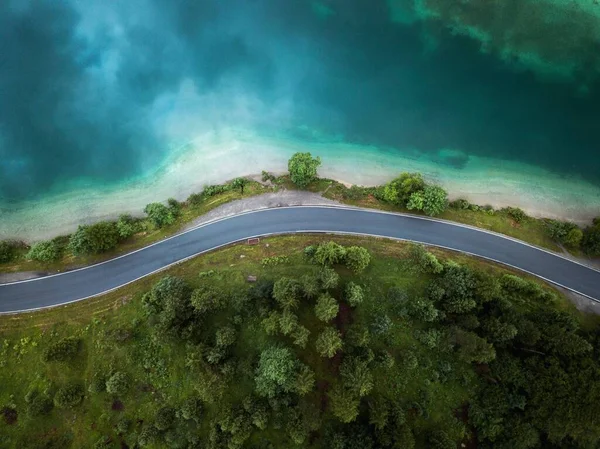Beautiful aerial view of road between green summer forest and blue lake in Austria, Europe, Plansee lake 