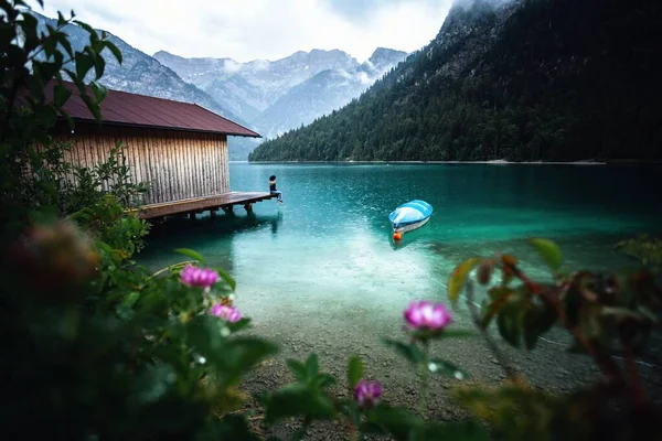 Young caucasian female relaxing on pier near the mountain lake. Vacation, travel concept