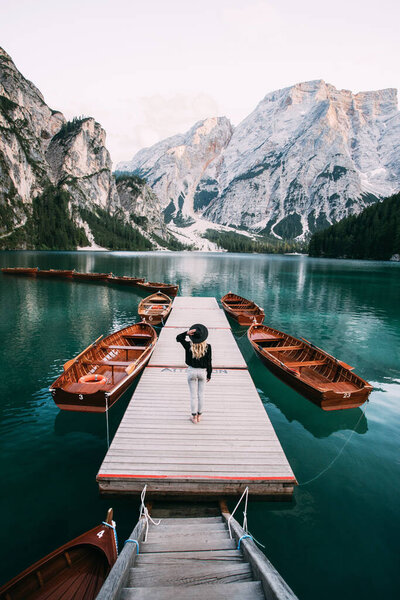 Woman standing on a wooden pier at the famous place in the Dolomities, Lago Di Braies lake, Italy, Europe
