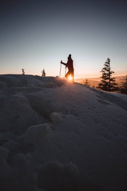 Woman with walking poles enjoying the majestic sunset during winter at Hasmas mountains, Transylvania, Romania. Outdoor, Adventure concept