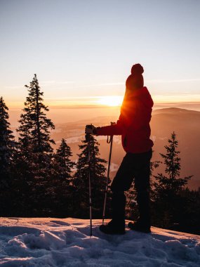 Young hiker woman with walking poles enjoying the majestic sunset during winter at Hasmas mountains, Transylvania, Romania. Outdoor, Adventure concept