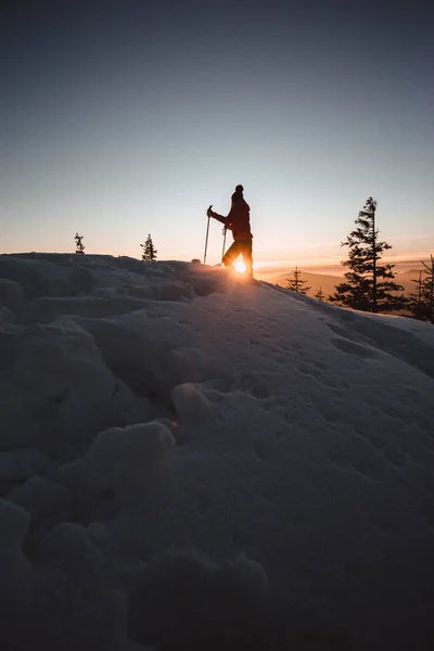 Woman with walking poles enjoying the majestic sunset during winter at Hasmas mountains, Transylvania, Romania. Outdoor, Adventure concept