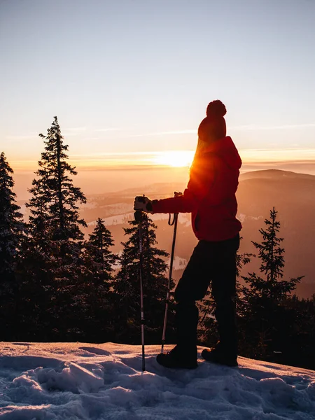 Young hiker woman with walking poles enjoying the majestic sunset during winter at Hasmas mountains, Transylvania, Romania. Outdoor, Adventure concept