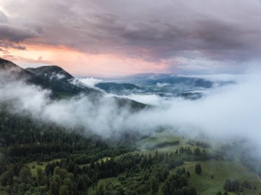 Dağlarda beyaz bulutlarla güzel bir gün batımı