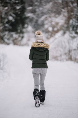 Kış ormanlarında yürüyen bir kadının arka görüntüsü