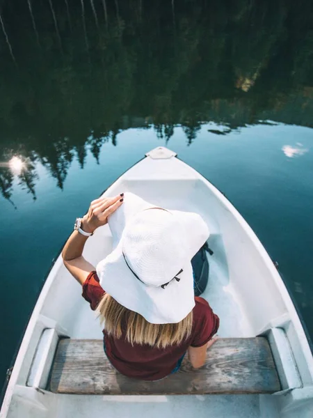 top view of blonde woman in hat sitting in a boat