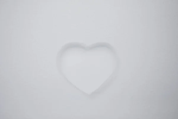 Heart shape on natural pure white soft snow surface in a cold weather day. Symbol of love in winter holiday season. Romantic outdoor concept for Valentine\'s day with copy space.