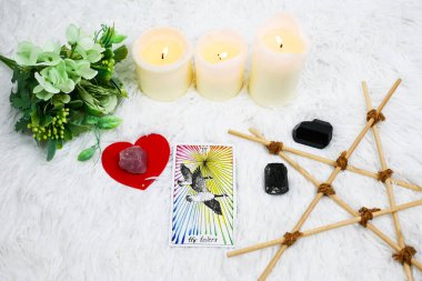 Buket çiçekleri vazosu, putperest ahşap yıldız, beyaz mumlar alev, aşıkların tarot kartı, tarot okuma, kristal siyah turmalin, kalp şeklindeki pembe kuvars, aşk ilişkileriyle sembolik sorgulama