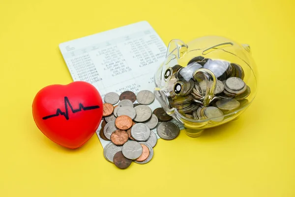 Coins in piggy savings jar, account book, pulse heart rate heart, health insurance, medical expenses, tax concept, financial concept,