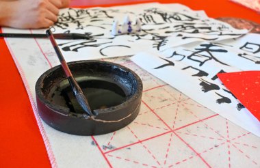 Hand holding brush while writing calligraphy