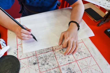 Hand holding brush while writing calligraphy