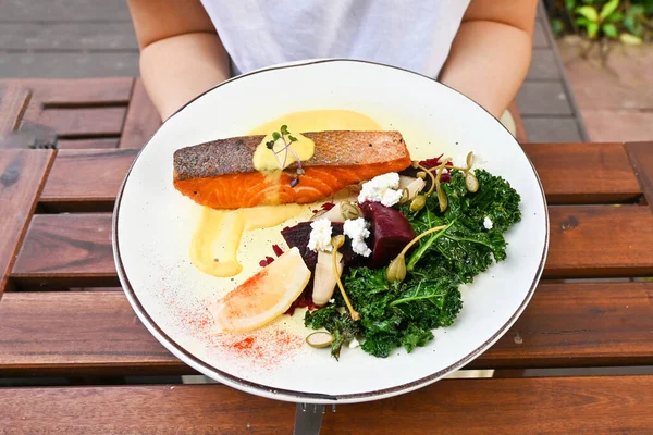 Woman hold the healthy crispy salmon with kale. Healthy eating lifestyle habit. Self love, self care for physical, mindfulness eating. Concept. Healthy nutrition, diet good nutrition.