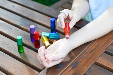 Woman use red herbal natural essentials oil roll on her wrist, healing sacral chakra. Mindfulness spiritual living. awakening