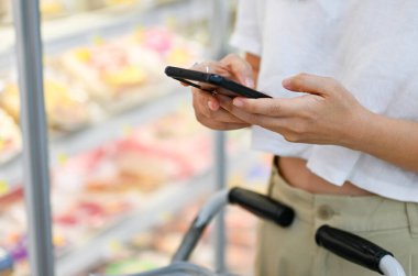 Woman using smartphone for checking, comparing price. searching information for grocery shopping.Technology for modern mindfulness living lifestyle.