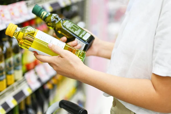 Woman reading nutrition facts on label on oil bottle for grocery shopping. Nutrition healthy lifestyle. Mindfulness living.