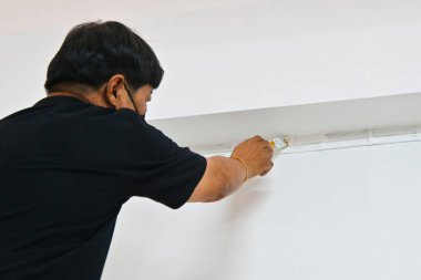 Male hand painting wall with paint brush. Painting house, apartment, renovating with white colour paint