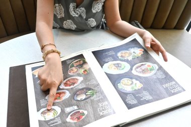 Lokantada yemek siparişi veren kadınları işaret ediyor. Menüde İngilizce çevirili thai dili var.