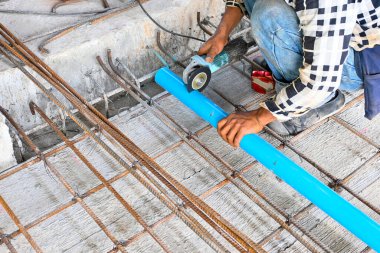 İnşaat alanında öğütücüyle boru kesen bir işçi.