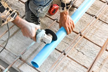 İnşaat alanında öğütücüyle boru kesen bir işçi.