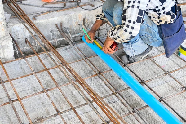 Worker measuring pipe with measure tape pipe at construction site