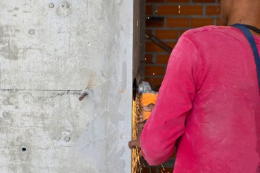 İşçiler çeliği çimento duvarında öğütüyor. Güvenlik için göz koruması takıyorlar..