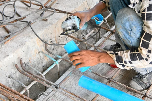 Worker cutting pipe with grinder at construction site