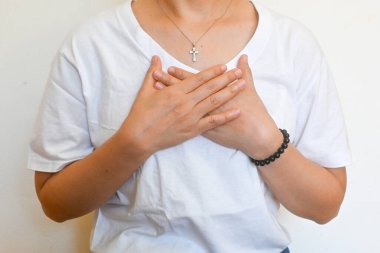 Kristal şifa kolyesi takan Asyalı kadın, kendini sevme alıştırması, kişisel bakım meditasyonu, eller çapraz sevgiyi simgeliyor kendimi, kalp çakramı. Alternatif aura iyileşmesi. Olumlu ruhani farkındalık