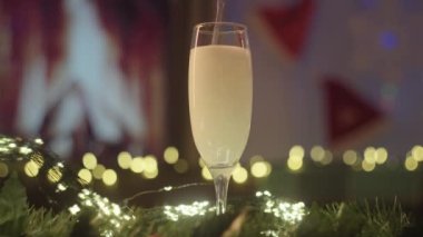 The glass is filled with champagne against Christmas decorations. The mans hand picks up a glass of champagne. High-quality 4k footage