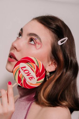 young beautiful woman with red lipstick and lollipop on white background 