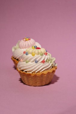 a delicious and colorful cupcake on pink background