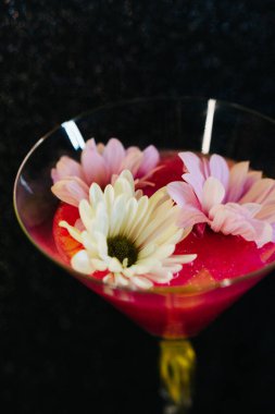 close up of a flower in a glass with a red rose
